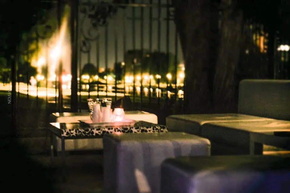 Outdoor seating area at night featuring a table with two lit candles, chairs around it, and a quiet, softly illuminated background—perfect for intimate event planning or branding events.